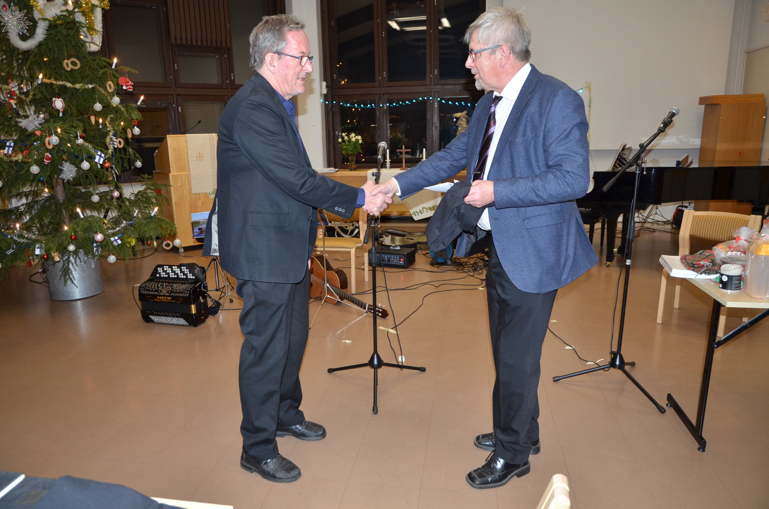Seuran kitaristia ja solistia Jouko Oikarista muistettiin 70-vuotismerkkipäivän johdosta. Onnittelijana puheenjohtaja Erkki Oikarinen.